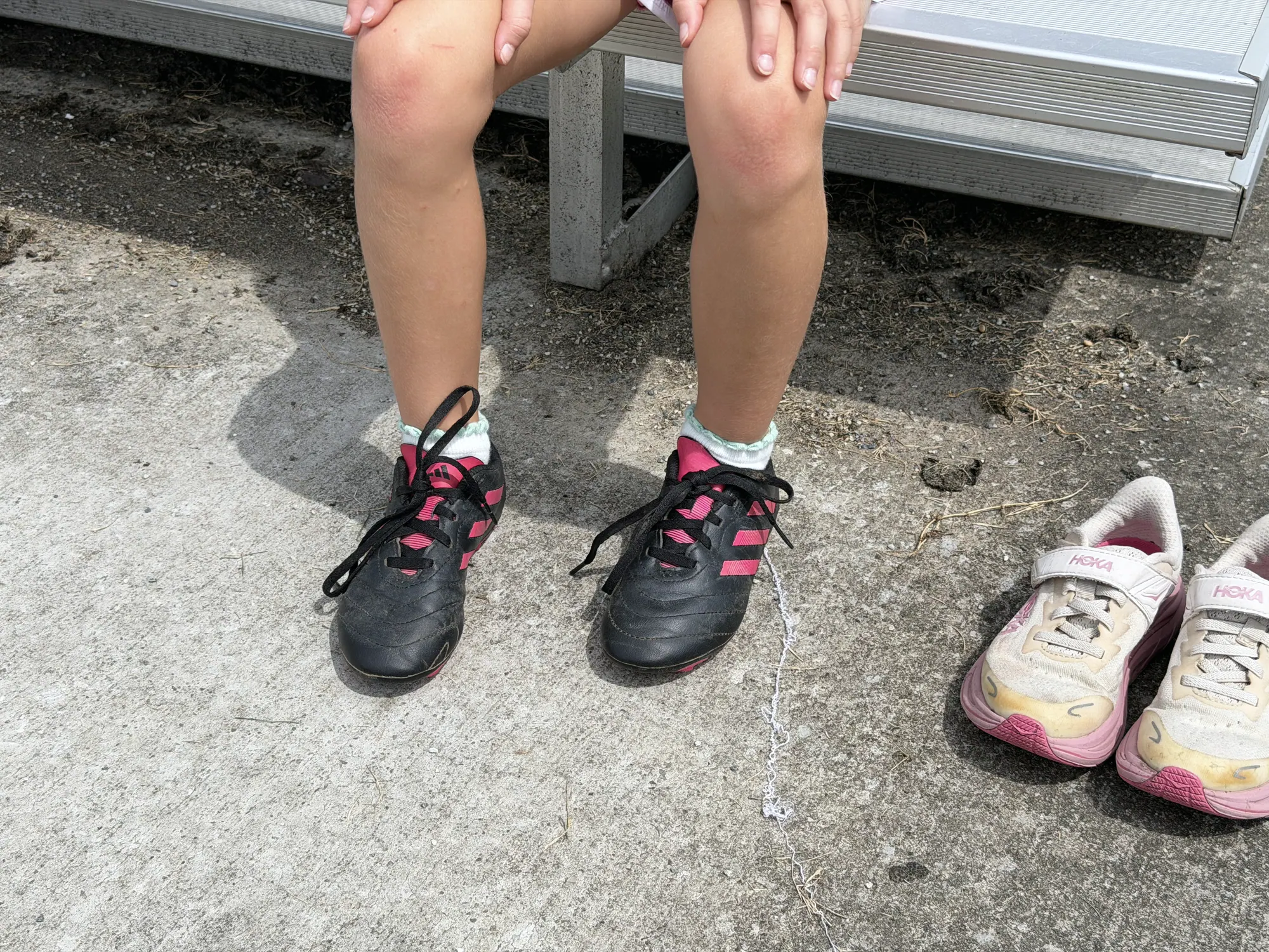 A player standing in a newly fitted pair of donated cleats, the outgrown shoes set down beside them